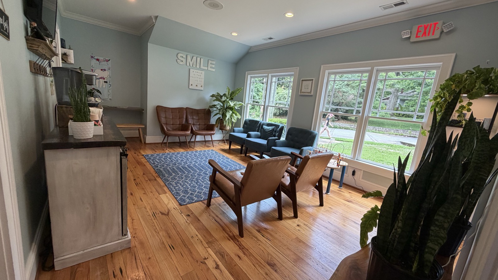 The Decatur Smiles waiting room — mid-century leather chairs, blue loveseats, a SMILE wall sign, and big windows with greenery